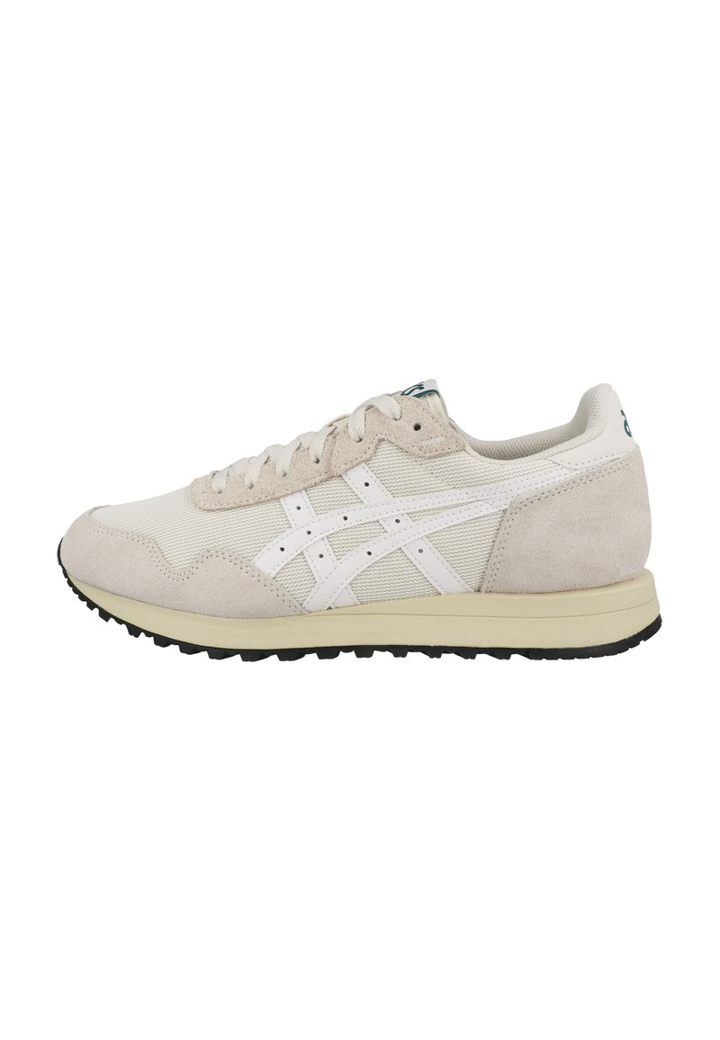 Zapatilla deportiva beige con parte superior de malla y acentos de ante, marca blanca, puntera redonda, cordones planos y suela de goma negra texturizada.