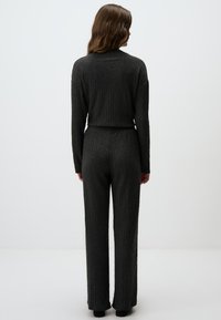 Grijze, textuurgebreide set bestaande uit een aansluitend langemouwen top met ronde hals en hoge taille wijde broek, beide met een zigzagpatroon.