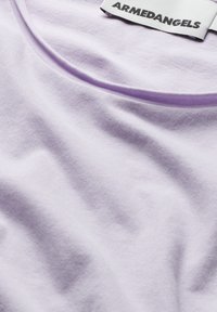 Lavendel T-shirt met een gladde, zachte textuur en een ronde halslijn. Bevat een contrasterende paarse kraag en een merklabel dat aan de achterkant is gestikt.
