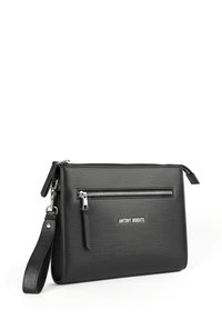 Bolso de mano sintético negro con un acabado texturizado, que presenta un cierre superior con cremallera, un bolsillo frontal con cremallera y una correa para la muñeca desmontable. Nombre de la marca exhibido.