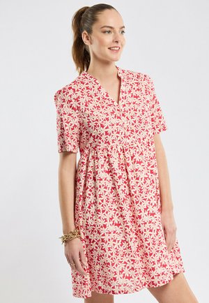 Robe florale rose avec un décolleté en V, des manches courtes et une taille froncée. Présente des motifs de fleurs blanches et jaunes sur un fond clair.