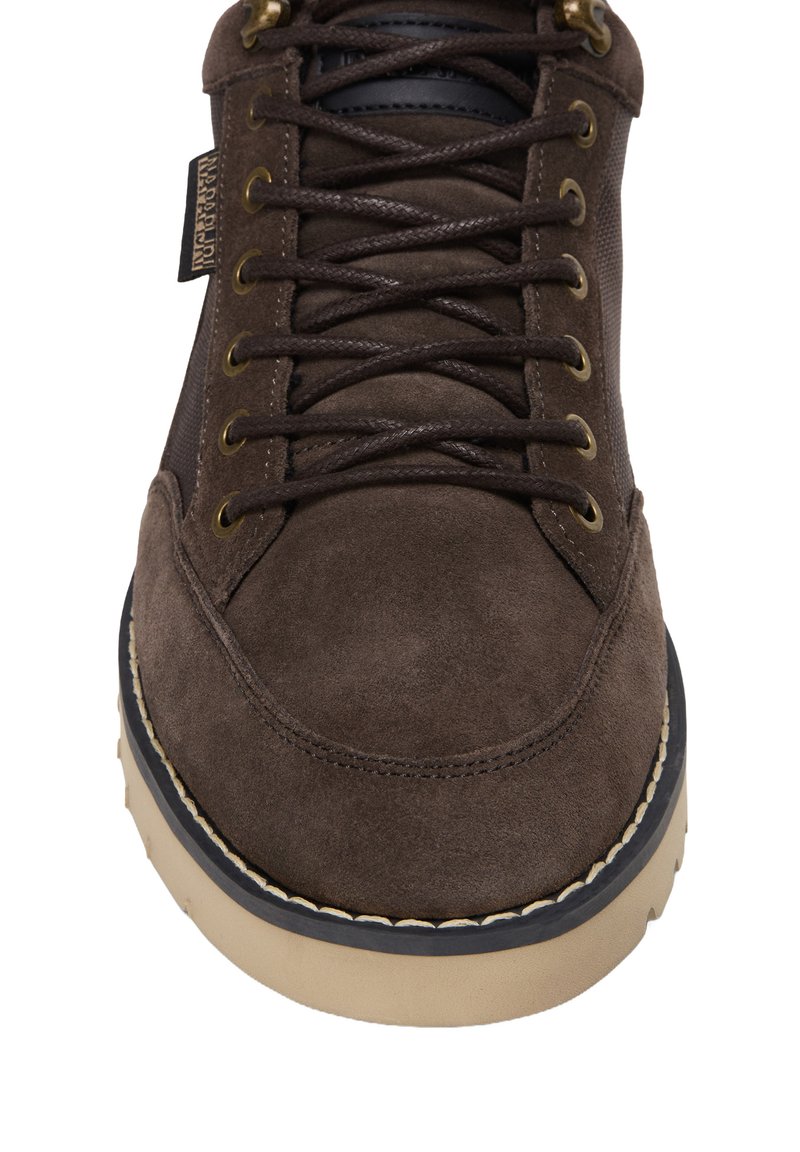 Scarpa in suede marrone con punta arrotondata, occhielli in metallo e lacci scuri. Presenta una suola in gomma beige a contrasto e un design superiore testurizzato.