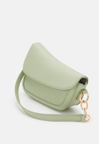 Piccola borsa a tracolla in pelle verde chiaro con chiusura a pattina, tracolla removibile e dettagli in catena e anelli color oro su sfondo bianco.