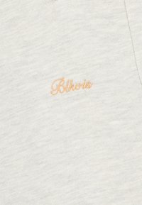 Tela de color gris claro con una textura fina que presenta un logo bordado "Blkwtz" en un suave naranja. Diseño simple, con costura en forma ovalada.
