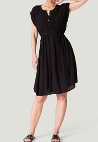 Robe noire à manches courtes, devant boutonné, design plissé au niveau du corsage, taille nouée, jupe fluide et silhouette décontractée.