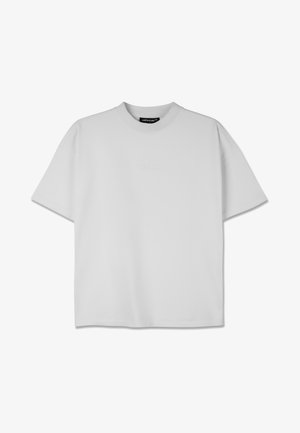 Biela oversize tričko s okrúhlym výstrihom, krátkymi rukávmi a jemne embosovaným logom na prednej strane. Vyrobené z mäkkého džersejového materiálu.