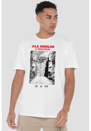 Man wearing white t-shirt with black and white Jurassic Park gate illustration and red text "Isla Nublar Grand Opening."
