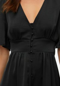 Vestido negro con un profundo escote en V, mangas cortas abullonadas y un cuerpo ajustado con una fila de botones cubiertos de tela en el frente.