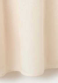 Tissu couleur crème avec une texture douce, suspendu librement avec de doux plis et des bords inférieurs arrondis.