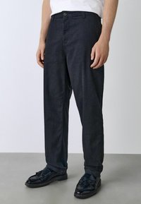 Dark blue denim trousers with a straight-leg cut, featuring a front button closure, belt loops, and subtle textured detailing.