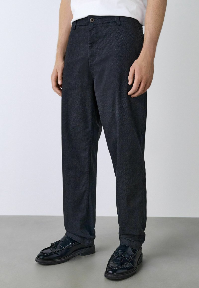 Dark blue denim trousers with a straight-leg cut, featuring a front button closure, belt loops, and subtle textured detailing.