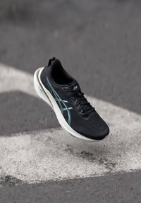 Černá sportovní bota s elegantním designem, s texturovaným svrškem, tyrkysovými akcenty a bílou podrážkou s gelovou polstrovanou komponentou.