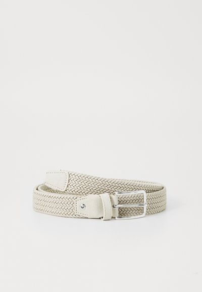 Ceinture élastique tissée en beige clair avec une boucle en métal argenté et un support en cuir ; présente un design flexible et texturé.