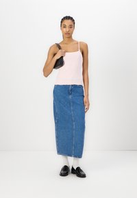Lys rosa ermeløs topp med scalloped kant, kombinert med et høy midje blå denim maxiskjørt. Svart håndveske og loafers fullfører antrekket.