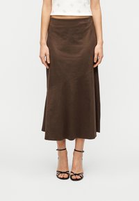 Καφέ μίντι φούστα σε μαλακό ύφασμα με γραμμή A, με πλαϊνές σκισμές και εμφανείς ραφές για επιπλέον υφή.