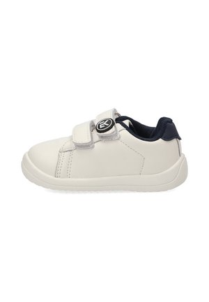 Zapatilla blanca infantil con dos tiras de velcro y cuello acolchado negro, mostrada de perfil sobre fondo blanco.