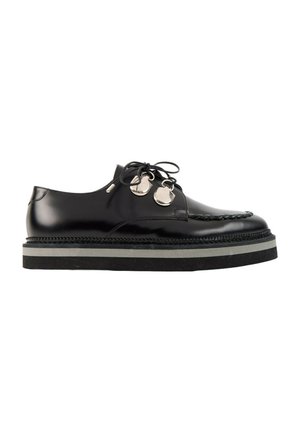 Chaussure noire en cuir à lacets avec semelle épaisse et œillets ronds métalliques, vue de profil sur fond blanc.