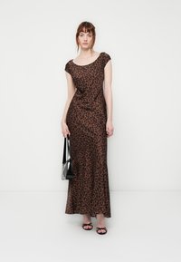 Dlhé šaty s leopardím vzorom v hnedých tónoch, s priliehavým strihom, okrúhlym výstrihom a krátkymi rukávmi; v kombinácii s čiernou kabelkou.