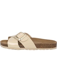 Beige patent slide sandal with a wide, crisscross strap and a metallic buckle accent. Cork sole for comfort with a textured finish.