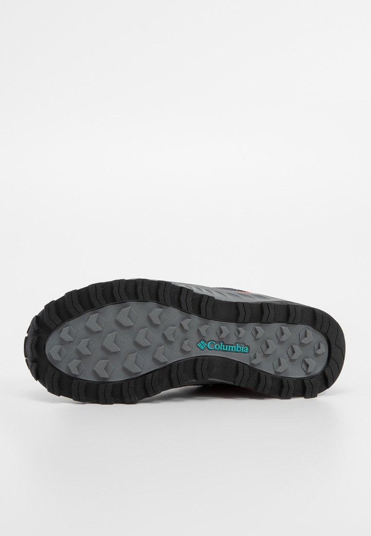 Suela de zapato de senderismo gris con un dibujo rugoso de goma negra y logo de Columbia en color verde azulado. Texturizada para ofrecer tracción en diferentes terrenos.