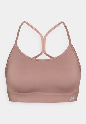 Soutien-gorge de sport rose clair avec une texture lisse, des bretelles croisées au dos et un petit logo blanc sur le bas à gauche.