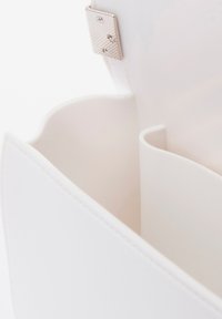 Interieur van een witte vegan leren handtas met zachte, ronde randen en een enkel compartiment. Voorzien van een metalen sluiting met een gematteerd oppervlak.