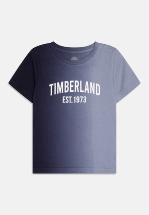 Rövid ujjú, kerek nyakú póló sötétkék és világoskék színátmenettel, elől fehér "TIMBERLAND EST. 1973" felirattal.
