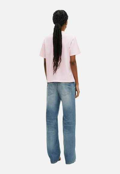 Camiseta de algodón rosa y jeans de pierna ancha en azul claro. La camiseta tiene mangas cortas y un corte relajado. Los jeans presentan un diseño de cinco bolsillos y un aspecto desgastado.