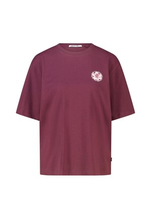 T-shirt à manches courtes couleur grenat avec un petit emblème floral rose clair et un texte circulaire sur la partie gauche de la poitrine.