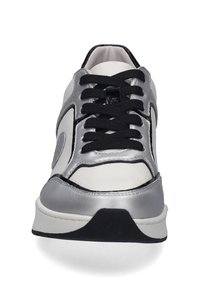 Bílé tenisky se stříbrnými syntetickými akcenty, černými tkaničkami, zaoblenou špičkou a texturovanou podrážkou. Charakteristické logo na boku.