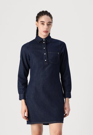 Donkerblauwe denim jurk met een kraaghalslijn, knoopsluiting, lange mouwen en een borstzak. Bevat contrasterende stikdetails.