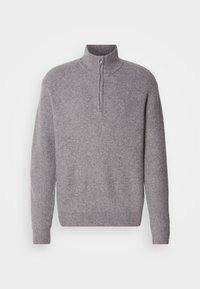 Grå strikkegenser med høy krage og halv glidelås. Ribbestruktur, lange ermer og en avslappet passform.