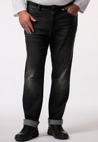 Mörka denimjeans med subtil blekning, rak passform och uppvikta benslut. Ett par svarta träningsskor fulländar looken.