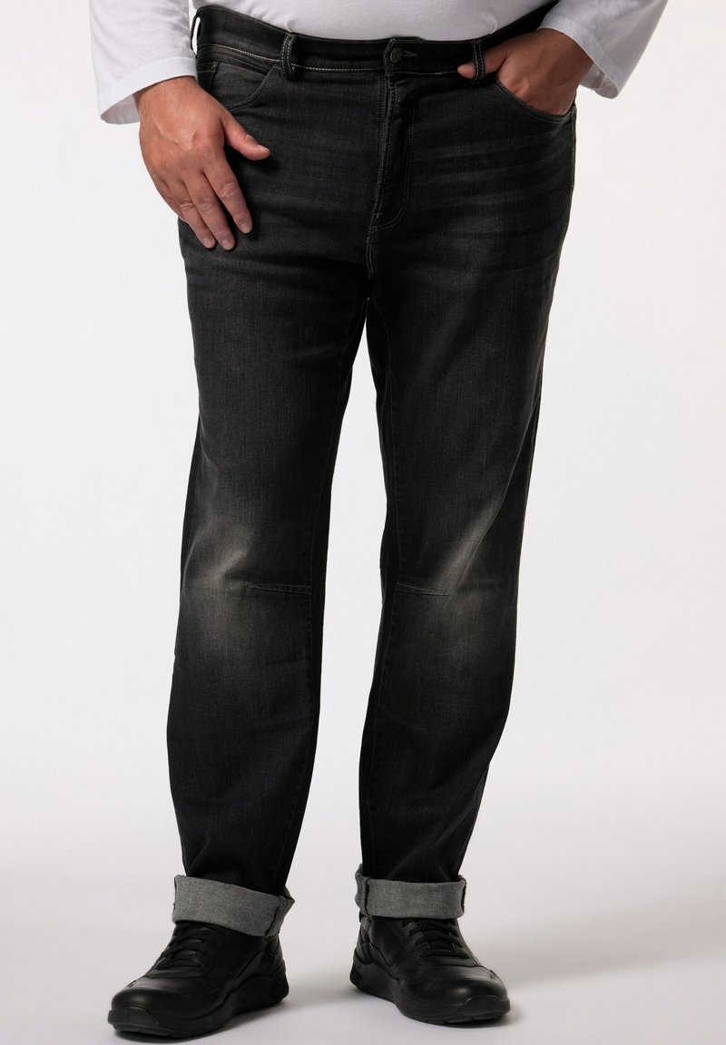 Mörka denimjeans med subtil blekning, rak passform och uppvikta benslut. Ett par svarta träningsskor fulländar looken.