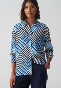 Camicia con bottoni, caratterizzata da un design geometrico con strisce diagonali blu e nere, realizzata in tessuto leggero, con colletto alla francese e maniche lunghe.
