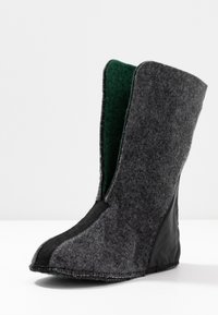 Doublure de botte en laine grise haute, avec panneaux noirs sur le bout et le talon, et intérieur en tissu vert, présentée debout sur une surface blanche.