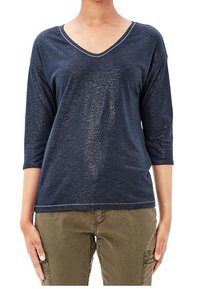 Navy blue V-neck long-sleeve top, made of textured fabric with subtle metallic threads. Features a relaxed fit and stitched neckline detail.