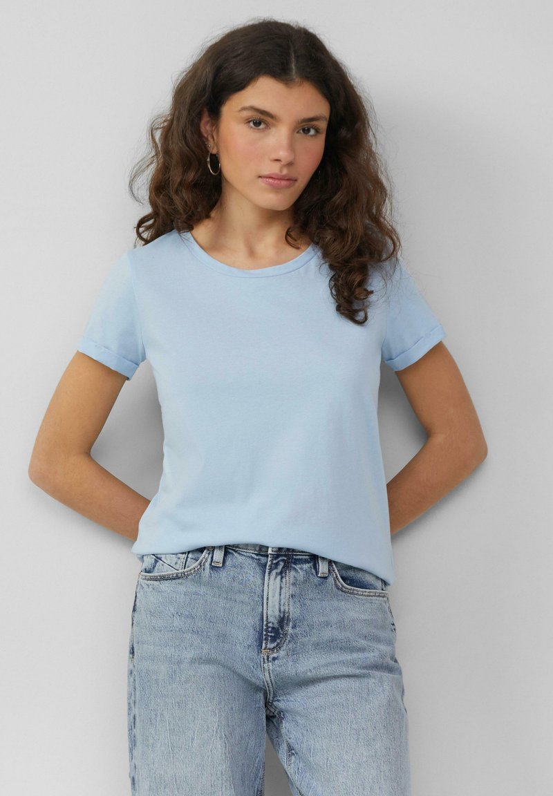 Lichtblauw, T-shirt met korte mouwen van zachte katoenstof met een ronde hals en omgerolde mouwen, gecombineerd met lichtblauwe versleten jeans.