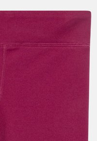 Leggings de color berry con textura acanalada, que cuentan con una cinturilla ancha y costuras reforzadas para mayor durabilidad.