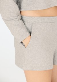 Grå bomullsshorts med sidofickor, elastisk midja och en mjuk textur. Nederkanten är avslutad med en ren kant.