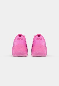 Pink athletic shoes featuring a textured synthetic upper, rounded heel, pronounced sole with wavy patterns, and "AM" branding at the back.