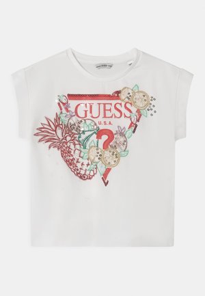 Chemise blanche à manches courtes avec logo GUESS rouge, texte U.S.A., point d'interrogation rouge et motifs de fruits tropicaux brodés sur le devant.