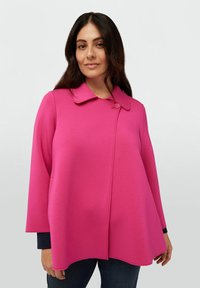 Rosa kappa med rundad krage, enkel knappstängning och utställd design. Mjuk tyg med slät yta och synliga sömdetaljer.