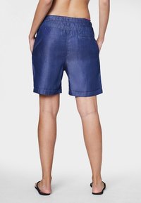 Shorts in denim blu scuro con una vestibilità comoda, vita elastica e orli arrotolati. Dotati di una tasca sul retro per una maggiore funzionalità.