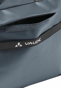 Grau wasserdichte Tasche aus strapazierfähigem Material, mit einem Klettverschluss und einem schwarzen Band mit dem Aufdruck "VAUDE" in Weiß.