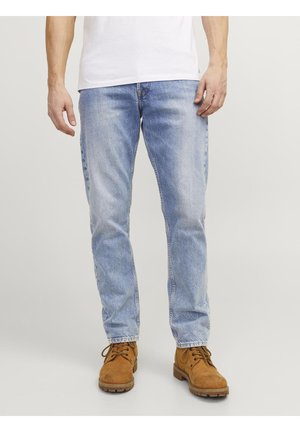 Ljusblå denimjeans med rak passform, lätt blekta, kombinerade med bruna mockastövlar med snörning och gummisulor.