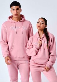 Sudaderas rosas y pantalones de chándal a juego, hechos de una suave mezcla de algodón. Presentan un bolsillo frontal y bordado blanco de "Project x Paris".