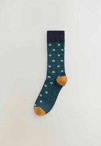 Dunkelblaue Socken mit hellblauen Punkten, versehen mit türkisfarbenen Streifen und einem braunen Fersen- und Zehenbereich. Der Stoff wirkt glatt mit einem gerippten Bündchen.