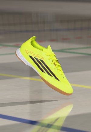 Scarpa da ginnastica giallo brillante con un design elegante, caratterizzata da strisce nere, una tomaia testurizzata e una suola in gomma coloratura.