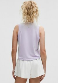 Lila mouwloze top met een textuurafwerking en perforerend ontwerp, gecombineerd met witte shorts. Eenvoudige, casual sportkleding.